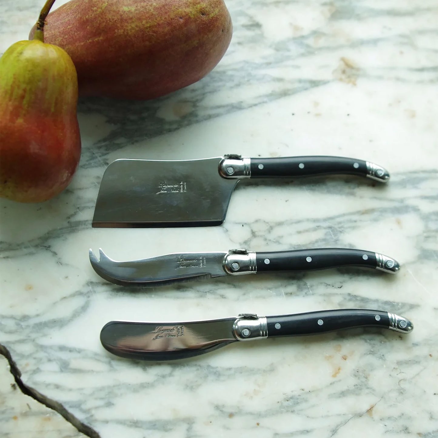 Lagouile 3 piece cheese knife set on a marble countertop with pears