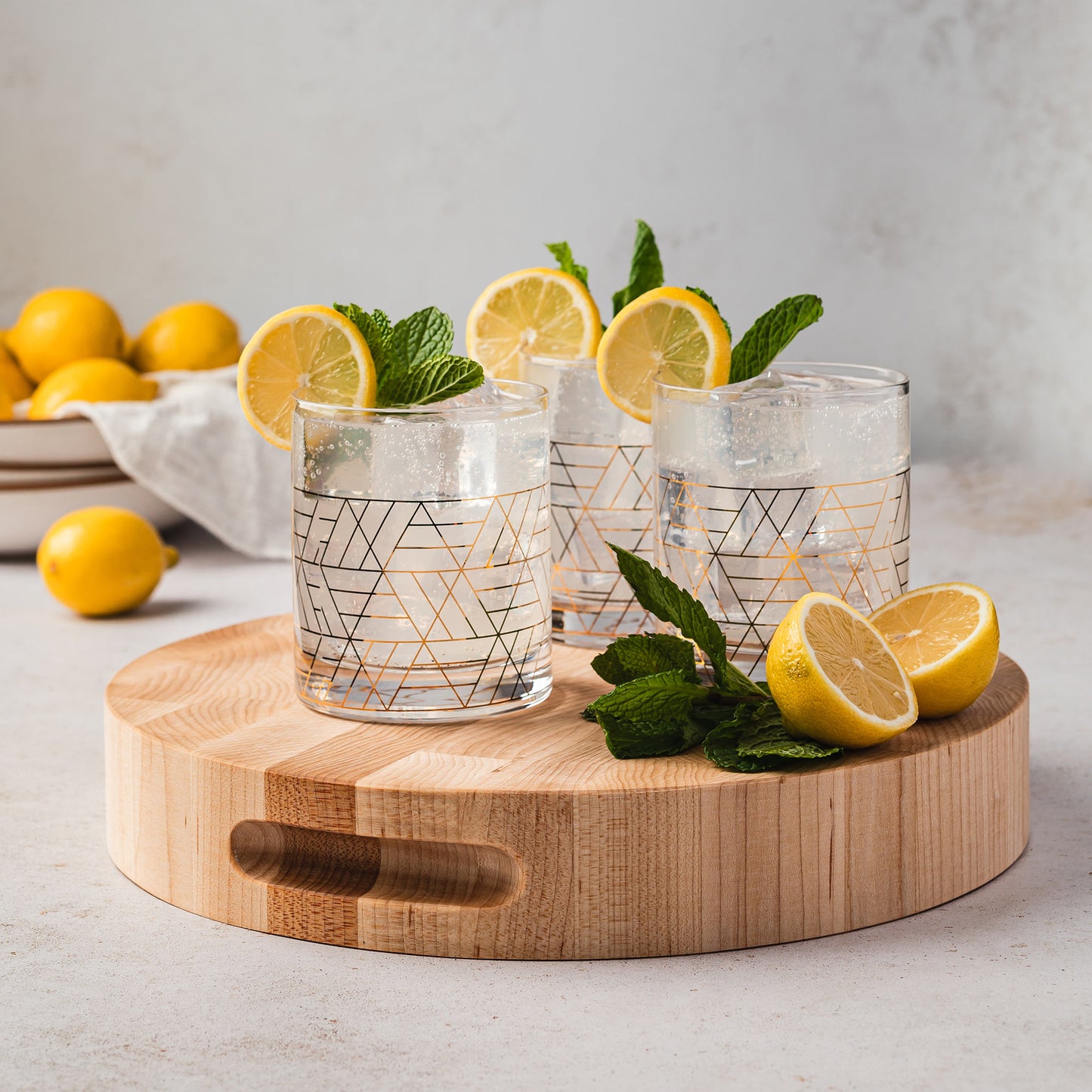 JK Adams PRO 12" Round Maple cutting board with 3 cocktail glasses and lemon garnish. 
