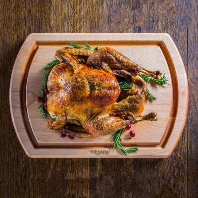 Roasted turkey with a golden-brown skin on a wooden cutting board, garnished with sprigs of rosemary and a few cranberries.